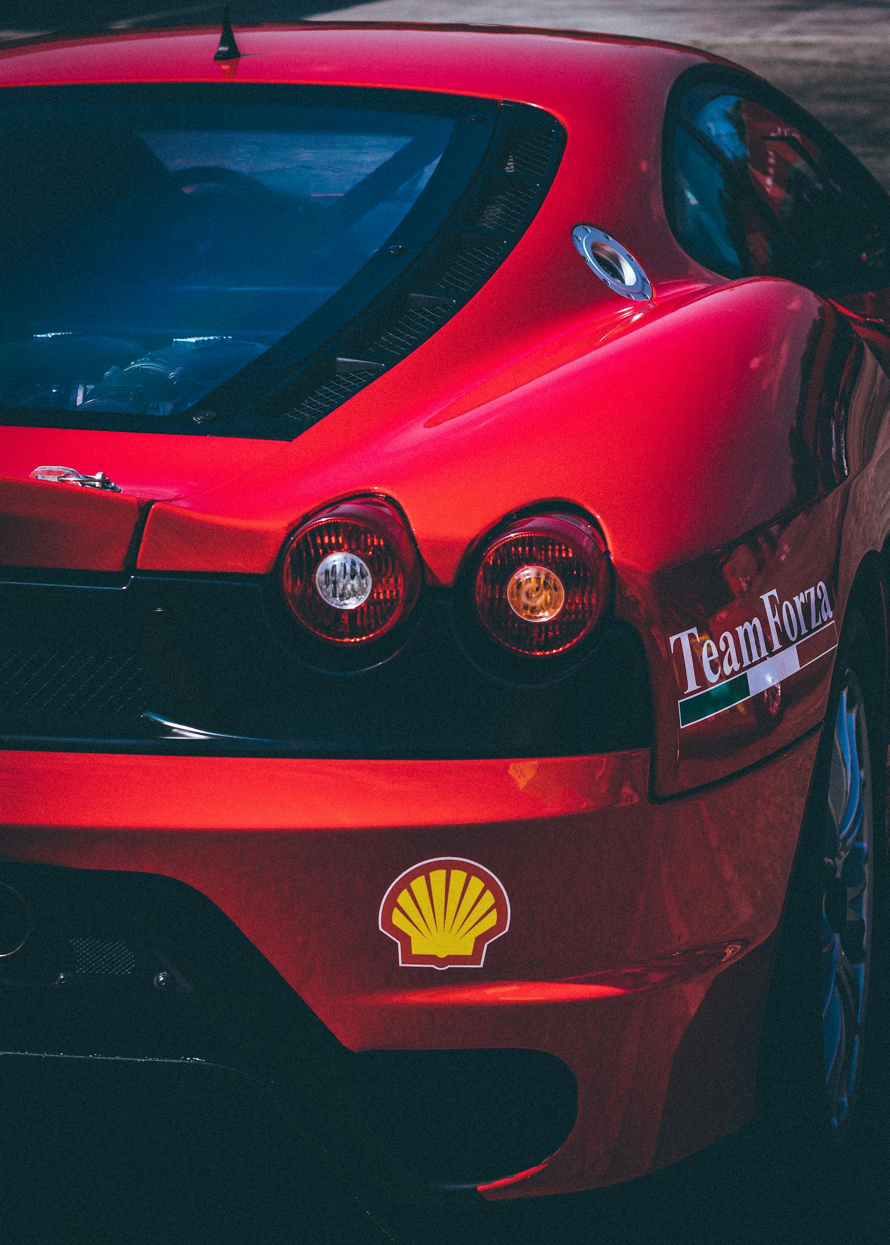 Detailed view of a red sports car featuring decals and taillights in a vertical shot.